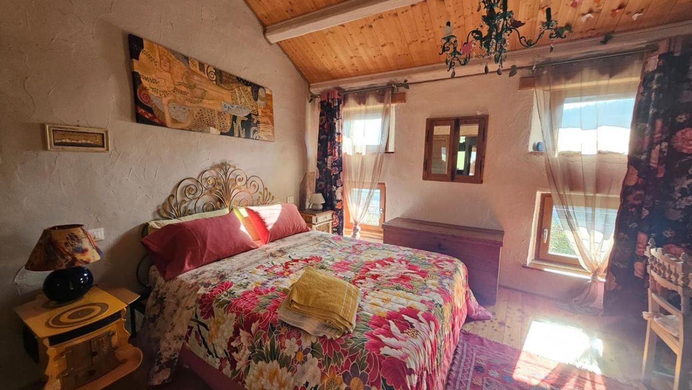 Camera con letto matrimoniale, copriletto a fiori e soffitto in legno