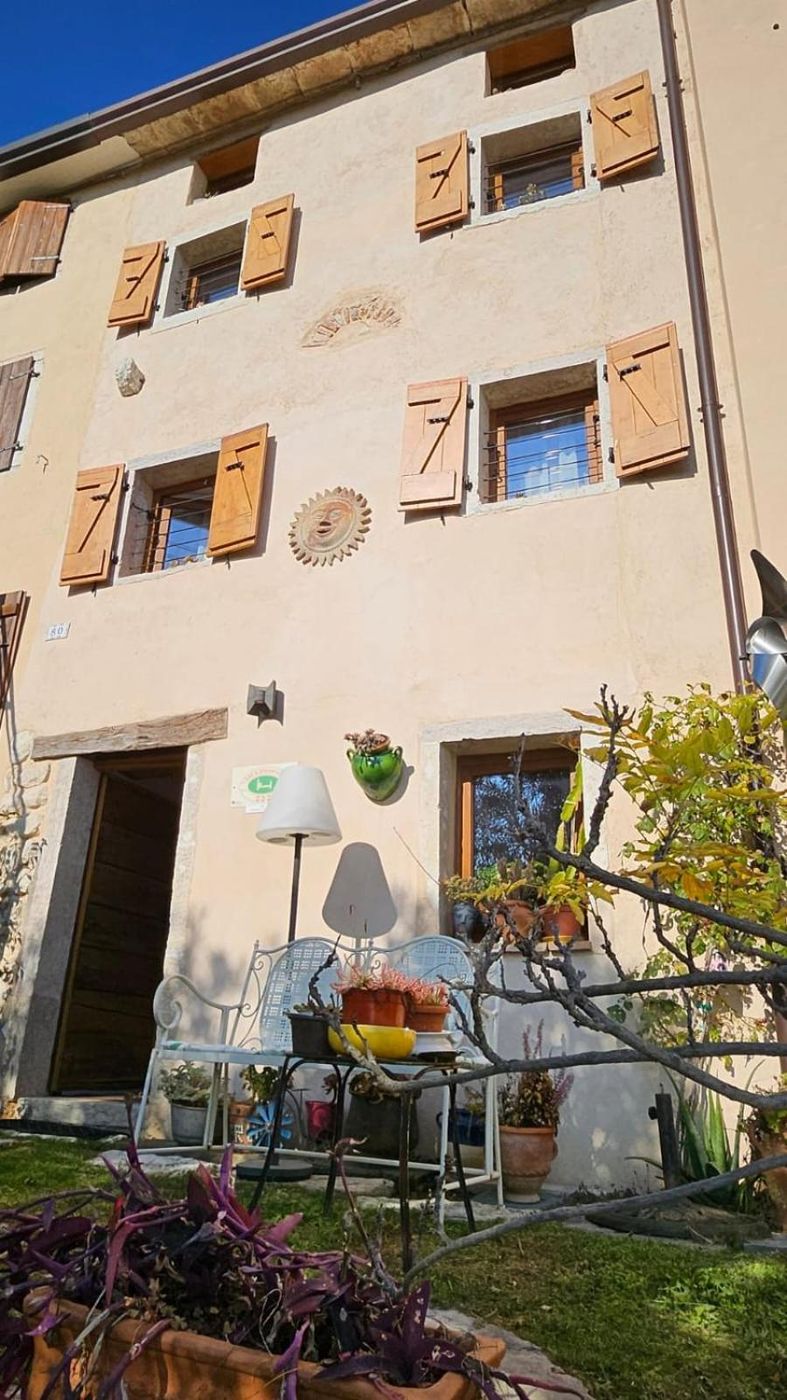 La facciata della casa con gli scuri in legno e il giardino