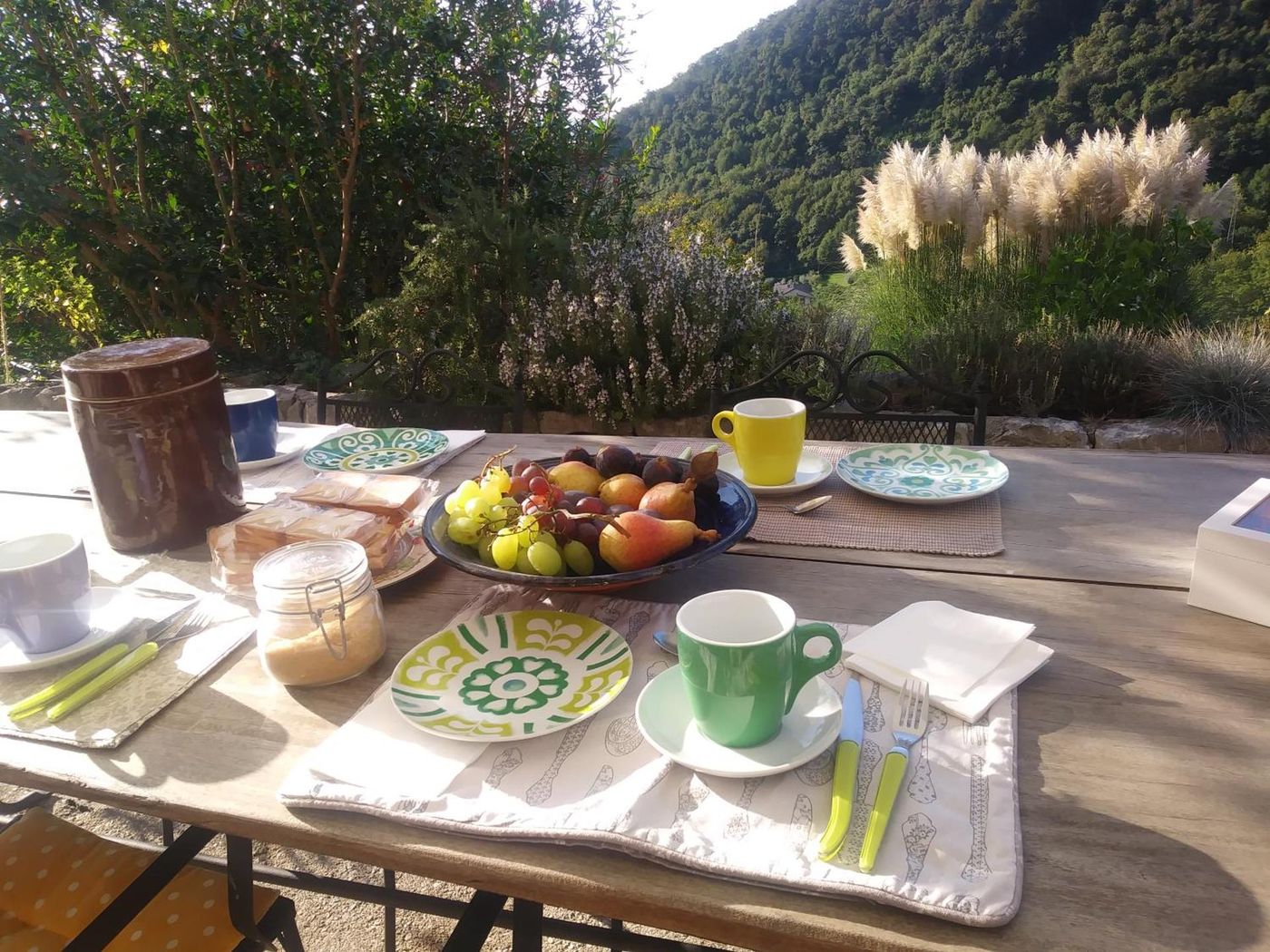 La colazione apparecchiata in terrazza con frutta e tazze colorate